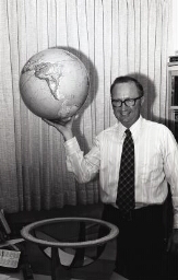 Portrait Ricks College faculty proudly holding a globe