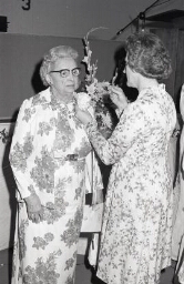 Alumni faculty pins a flower on another member