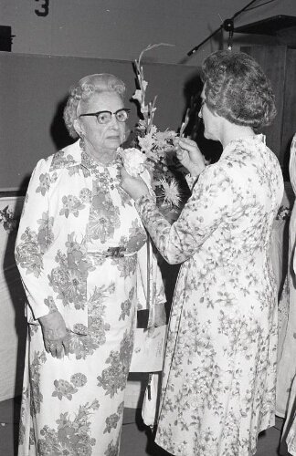 Alumni faculty pins a flower on another member