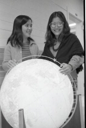 Portrait of students examining a globe