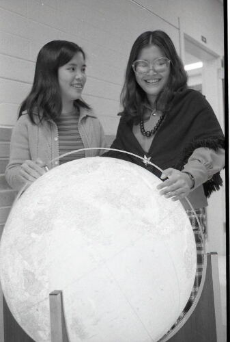 Portrait of students examining a globe